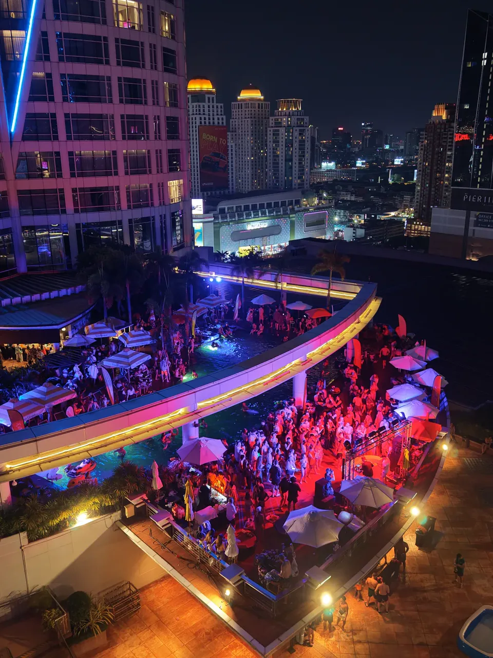 An aerial photo of the Centara rooftop pool party, with pink lights across the dance floor and Bangkok behind it